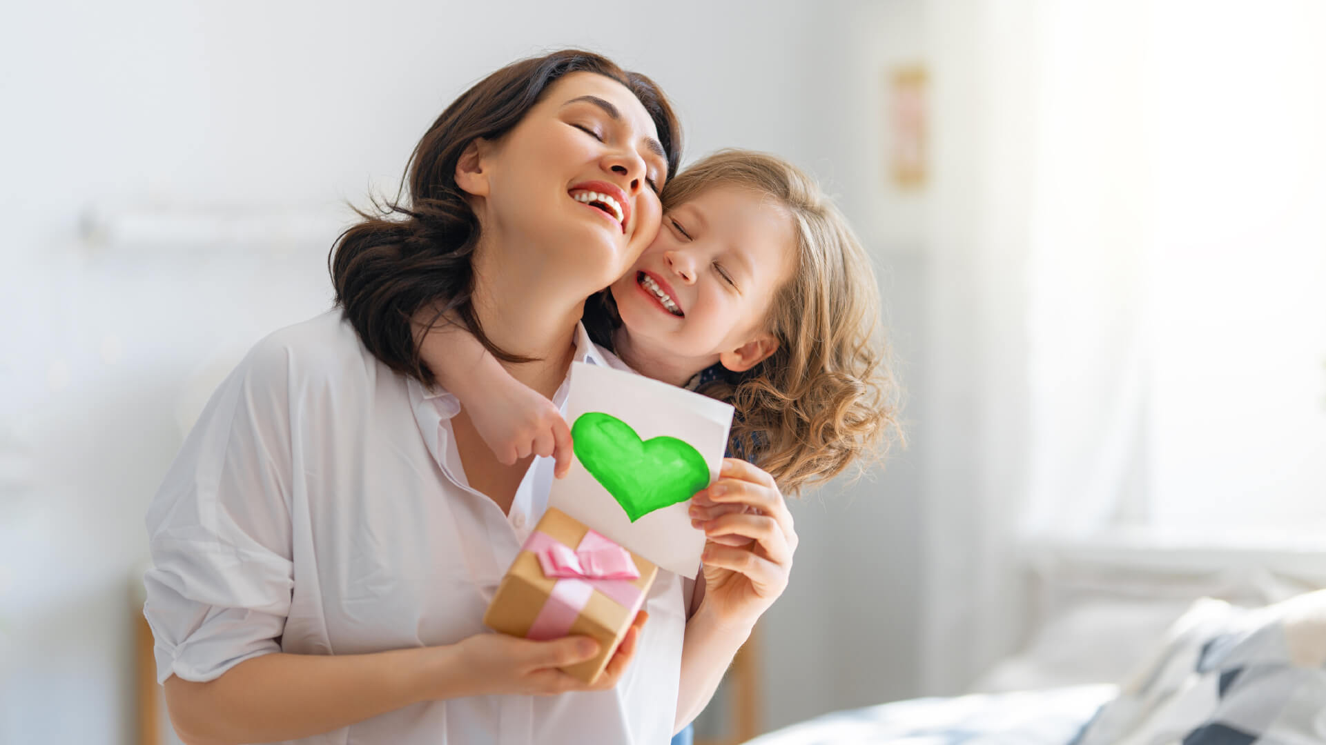 Mutter von Kind umarmt mit Geschenk in der Hand